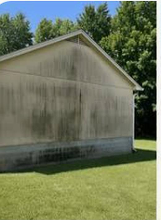 House gable end before washing, heavy black algae streaks running down the siding