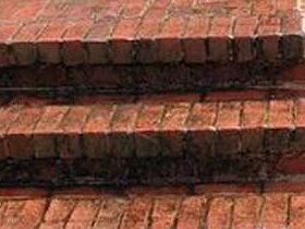 The same brick porch treads before washing, moss and mildew packed into the joints